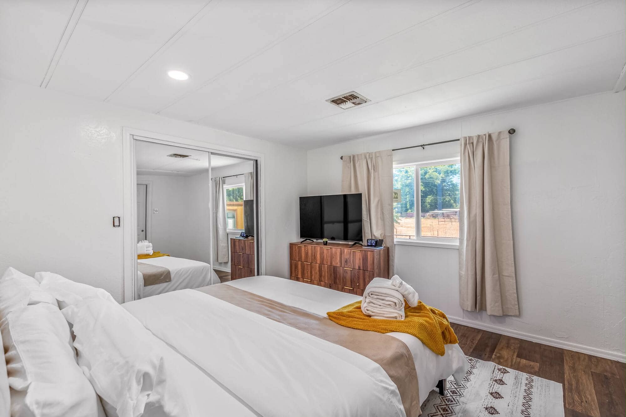 A guest bedroom with fresh white linens and folded towels laid out