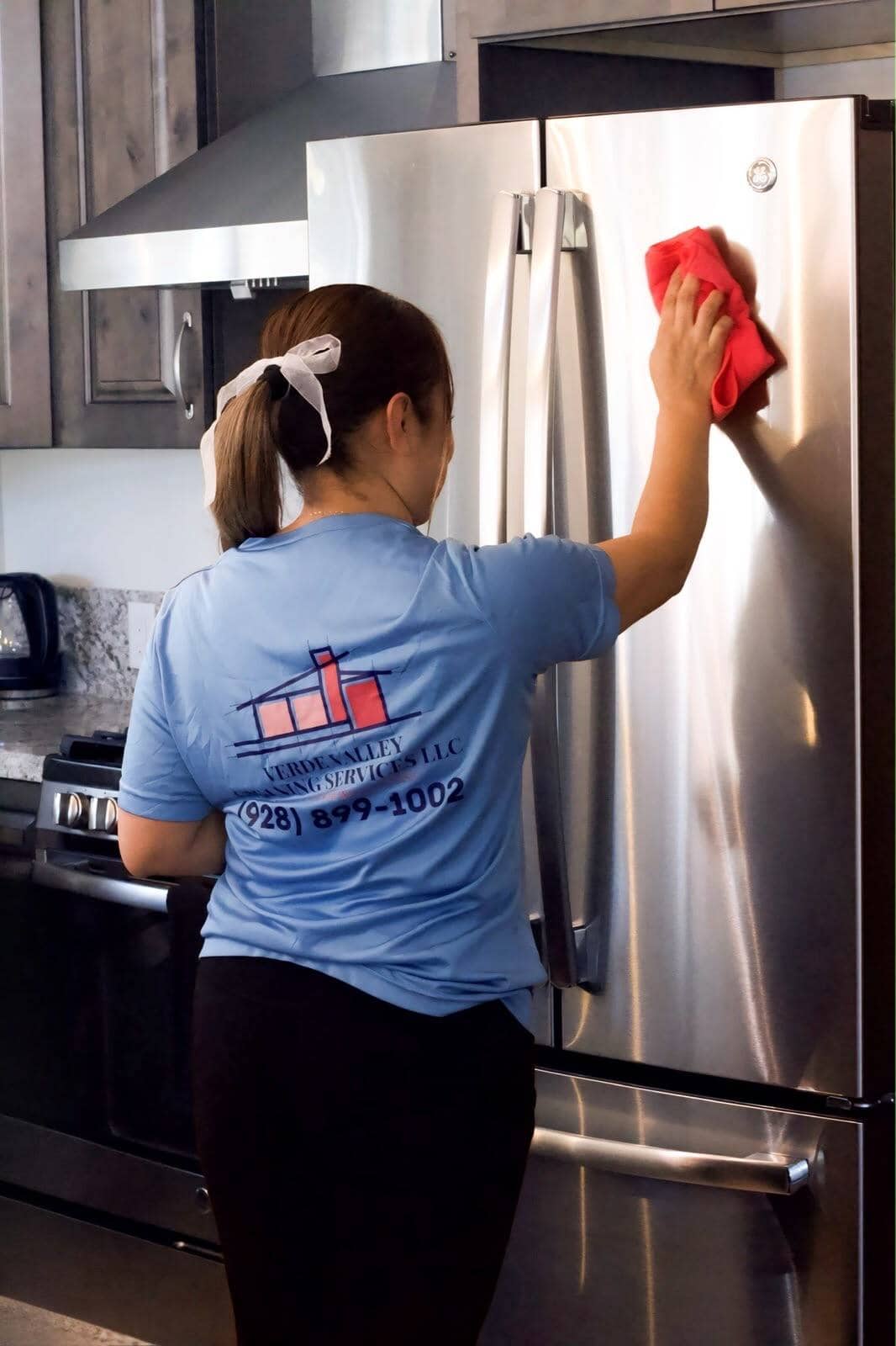 A Verde Valley Cleaning Services team member wiping down a stainless refrigerator