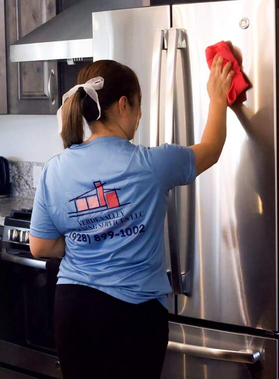 A Verde Valley Cleaning Services team member wiping down a refrigerator